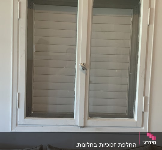 חלון זכוכית עם תריסים וספה מתחתיו